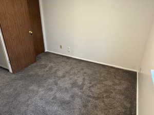 Unfurnished bedroom featuring dark colored carpet and baseboards