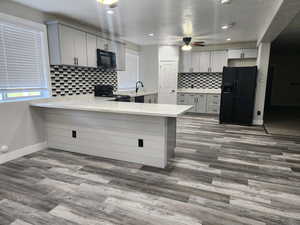 Kitchen featuring a peninsula, black appliances, light stone countertops, and plenty of natural light