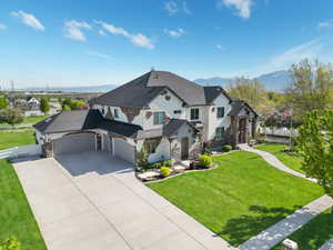 French country style house featuring stone siding, stucco siding, concrete driveway, a garage, and a mountain view