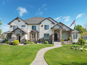 View of front facade featuring a front lawn, stone siding, and stucco siding