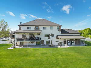 Rear view of house featuring a patio area, stucco siding, stone siding, and roof with shingles