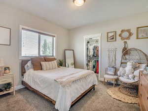 Carpeted bedroom featuring a spacious closet and baseboards