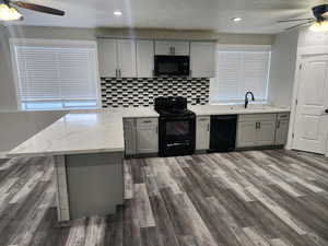 Kitchen with ceiling fan, a peninsula, gray cabinetry, and black appliances