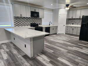 Kitchen featuring gray cabinets, a peninsula, black appliances, dark wood-style flooring, and ceiling fan