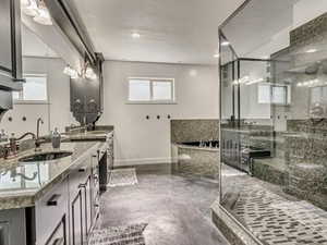 Bathroom with double vanity, concrete floors, a shower stall, and a garden tub