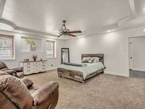 Carpeted bedroom featuring ornamental molding, a ceiling fan, and a raised ceiling