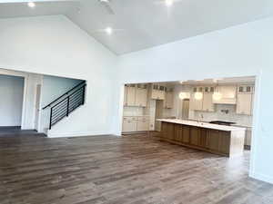 Kitchen with a kitchen island with sink, vaulted ceiling, open floor plan, dark wood-style flooring, and a ceiling fan