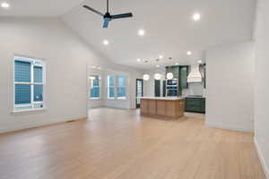 Kitchen featuring open floor plan, a center island, a ceiling fan, light countertops, and a high ceiling