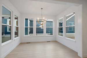 Unfurnished dining area with light wood finished floors and a chandelier