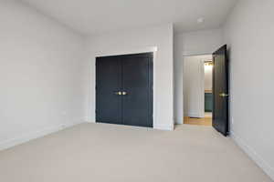 Unfurnished bedroom with light carpet and a closet