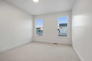 Spare room featuring light carpet and baseboards