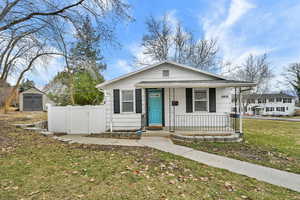 Bungalow-style house featuring a porch, a shed, and a gate