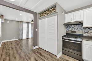 Kitchen with gas range, white cabinets, dark countertops, tasteful backsplash, and recessed lighting