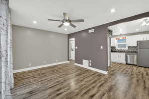 Unfurnished living room with ceiling fan, recessed lighting, and dark wood-type flooring