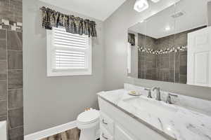 Full bath with vanity, a tile shower, dark wood-style flooring, and a bath