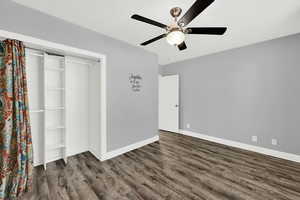 Unfurnished bedroom featuring a closet, ceiling fan, and dark wood-style flooring