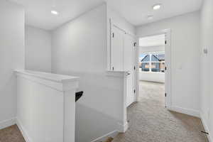 Hall with an upstairs landing, light carpet, and recessed lighting