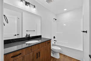 Full bathroom featuring vanity, dark wood-style flooring, shower / washtub combination, and recessed lighting