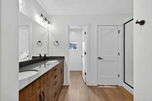 Bathroom with double vanity, light wood finished floors, and a stall shower