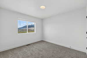 Spare room featuring a mountain view and dark colored carpet
