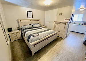 Bedroom with dark wood-type flooring, a closet, and a textured ceiling