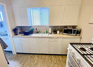 Kitchen with white gas stove, light countertops, and white cabinetry