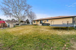 Rear view of property featuring a shed and a trampoline