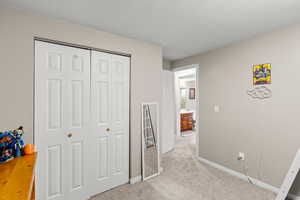 Unfurnished bedroom featuring light colored carpet, a closet, and a textured ceiling