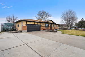 View of front of home featuring brick siding, driveway, a garage, and a chimney