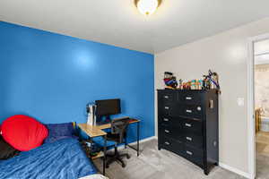 Carpeted bedroom featuring an office area and baseboards
