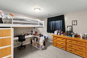 Bedroom featuring an office area, a textured ceiling, and light carpet