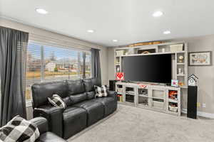 Carpeted living area with recessed lighting and baseboards