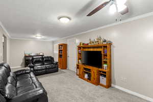 Living room featuring ornamental molding, carpet flooring, a textured ceiling, and a ceiling fan