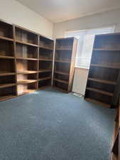 Unfurnished office with dark colored carpet and baseboards