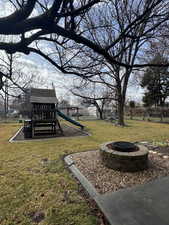 Fenced backyard with an outdoor fire pit and a playground
