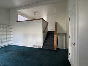 Staircase with carpet and a ceiling fan