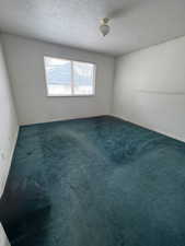 Carpeted empty room featuring baseboards and a textured ceiling