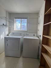 Laundry room featuring a textured ceiling, light flooring, and washing machine and dryer