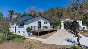 White brick exterior with a dark green roof, featuring a raised deck with black railings