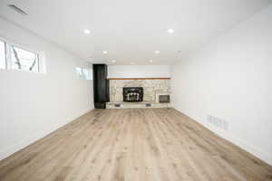 Unfurnished living room with light wood finished floors, recessed lighting, and a stone fireplace