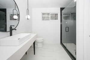 Bathroom featuring vanity, a stall shower, and light marble finish flooring
