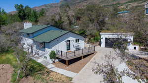 White stucco exterior with a dark green shingle roof, featuring an elevated deck with black railings