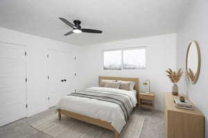 Bedroom featuring light carpet, a textured ceiling, ceiling fan, and multiple closets