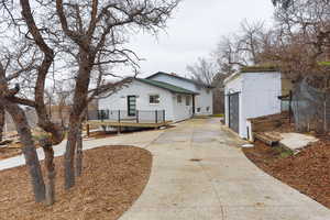 View of home's exterior featuring an outdoor structure, brick siding, a wooden deck, and driveway