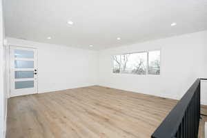 Empty room with light wood finished floors and recessed lighting