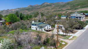 White exterior residence with a green roof and a prominent wooden deck