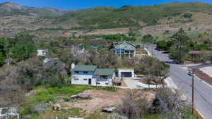 Two-story residential structure featuring a green roof, white siding, and an attached garage with a dark door