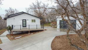 View of front of house featuring a wooden deck, brick siding, an outbuilding, and driveway