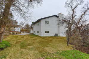 Back of house with a chimney, brick siding, a yard, and a patio area