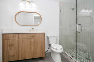 Full bathroom with vanity, a shower stall, and dark tile patterned flooring